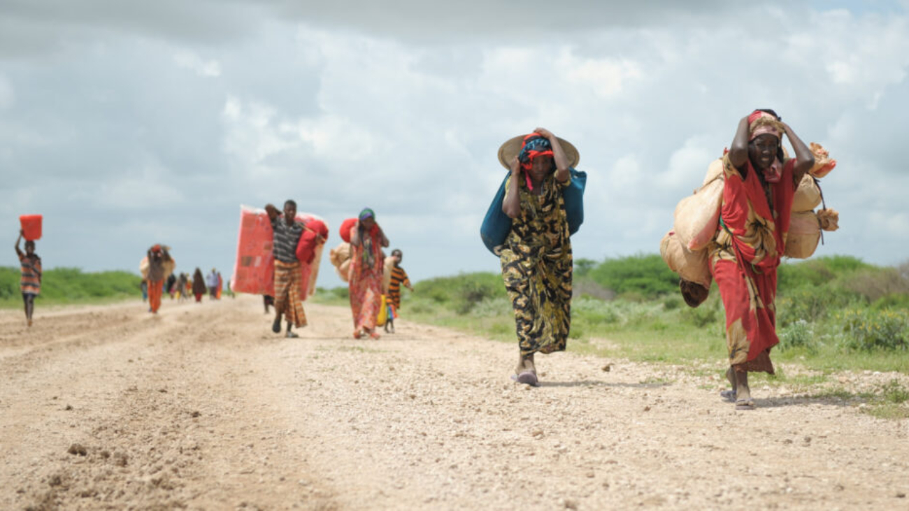 Women, walking with what possesions they can carry, arrive in a steady trickle at an IDP camp erected next to an AMISOM military base near the town of Jowhar, Somalia, on November 12. Heavy rains in Somalia, coupled with recent disputes between clans, has resulted in over four thousand IDPs seeking shelter at an AMISOM military base near the town of Jowhar, with more arriving daily. AU UN IST Photo / Tobin Jones. Original public domain image from Flickr